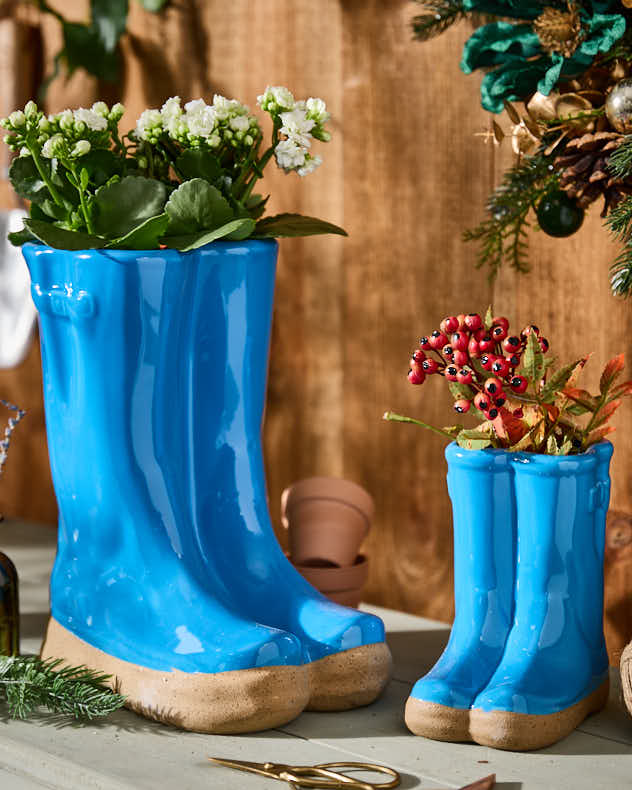 Kleine und große Blumentöpfe in leuchtend blauen Gummistiefeln