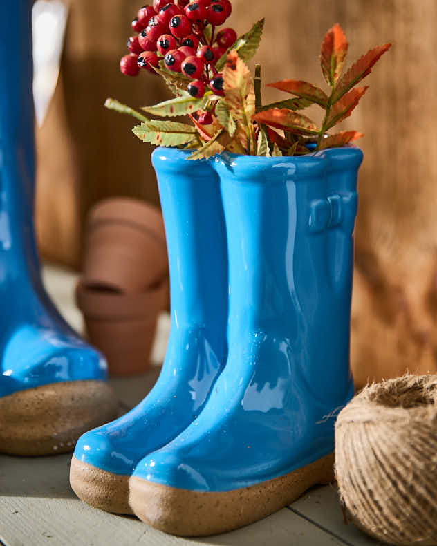 Kleine und große Blumentöpfe in leuchtend blauen Gummistiefeln