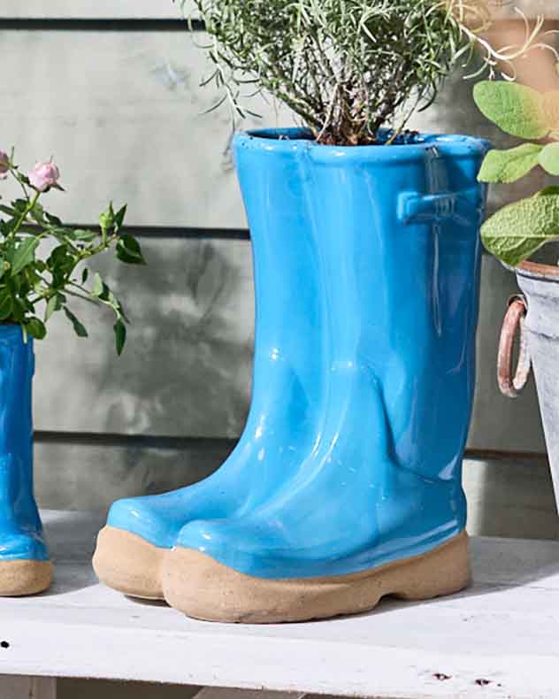 Kleine und große Blumentöpfe in leuchtend blauen Gummistiefeln