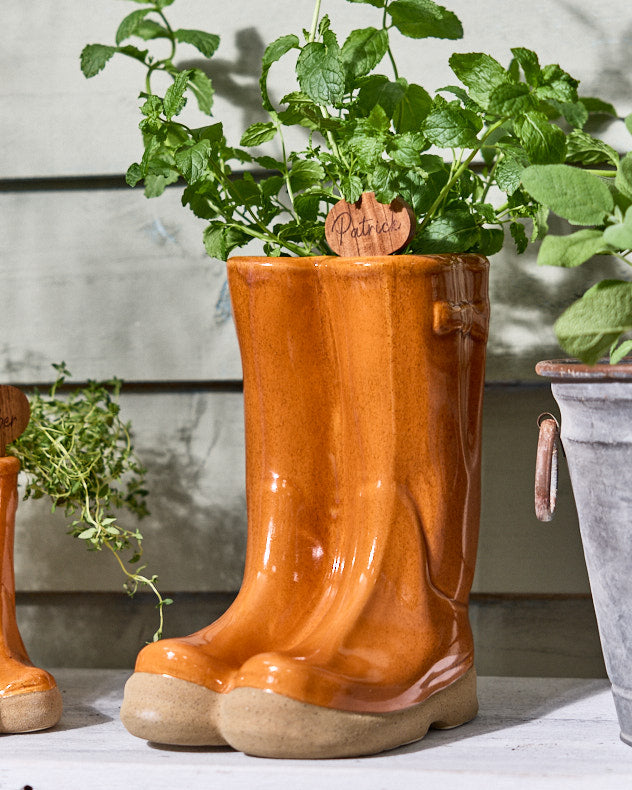 Großer orangefarbener Pflanzkübel für Gummistiefel mit personalisierter Markierung