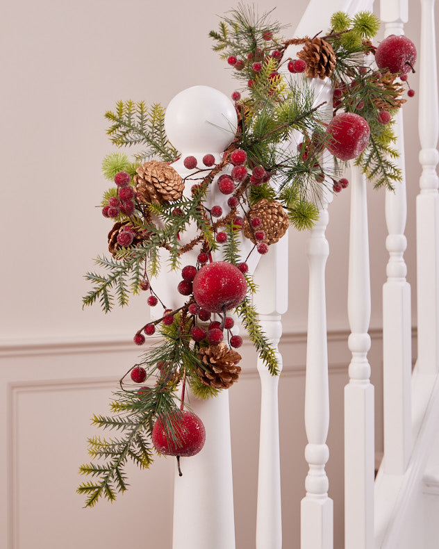 red berry, green foliage and red apple garland wrapped around banister